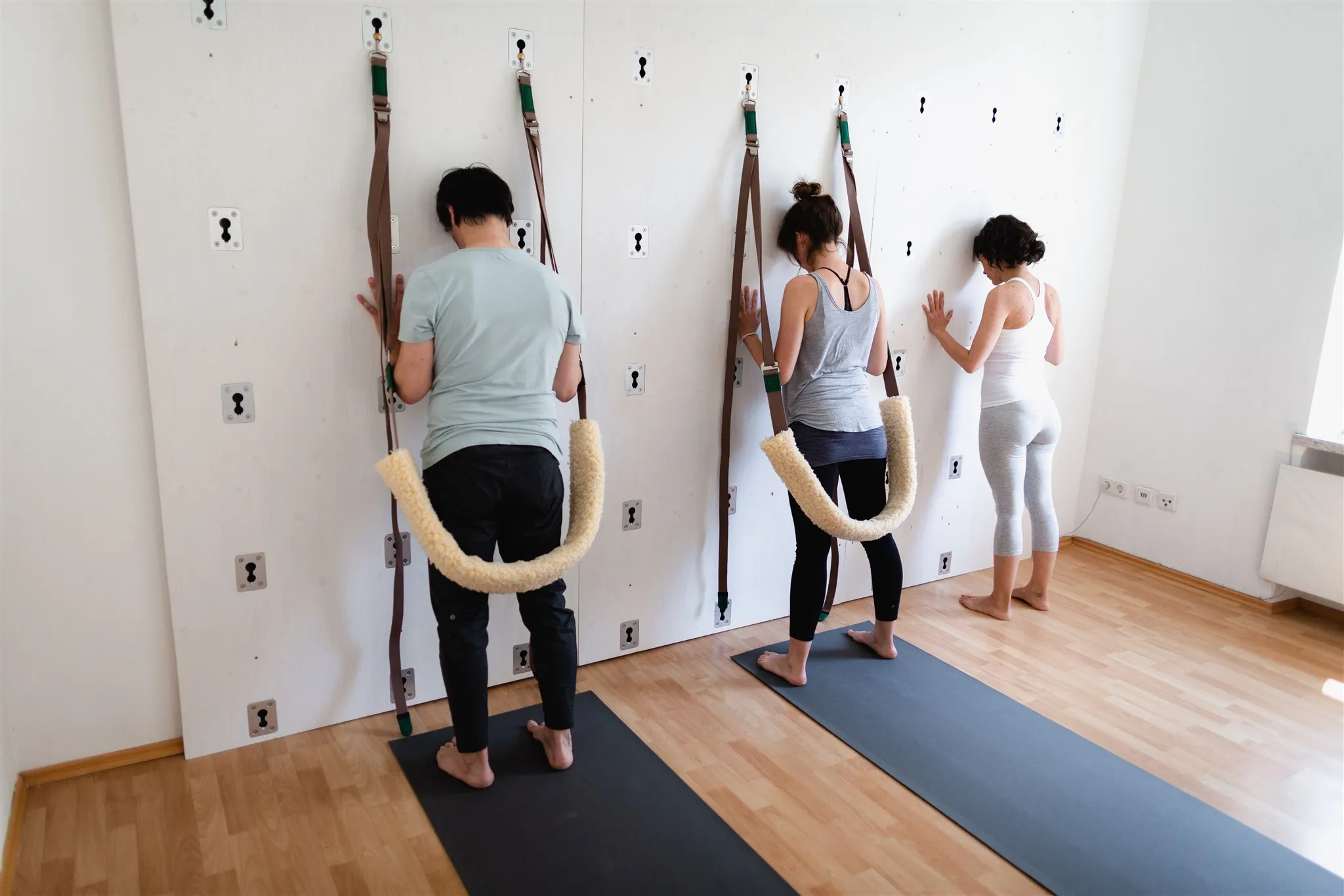 Kleine Gruppe übt gemeinsam an der Yoga Wall